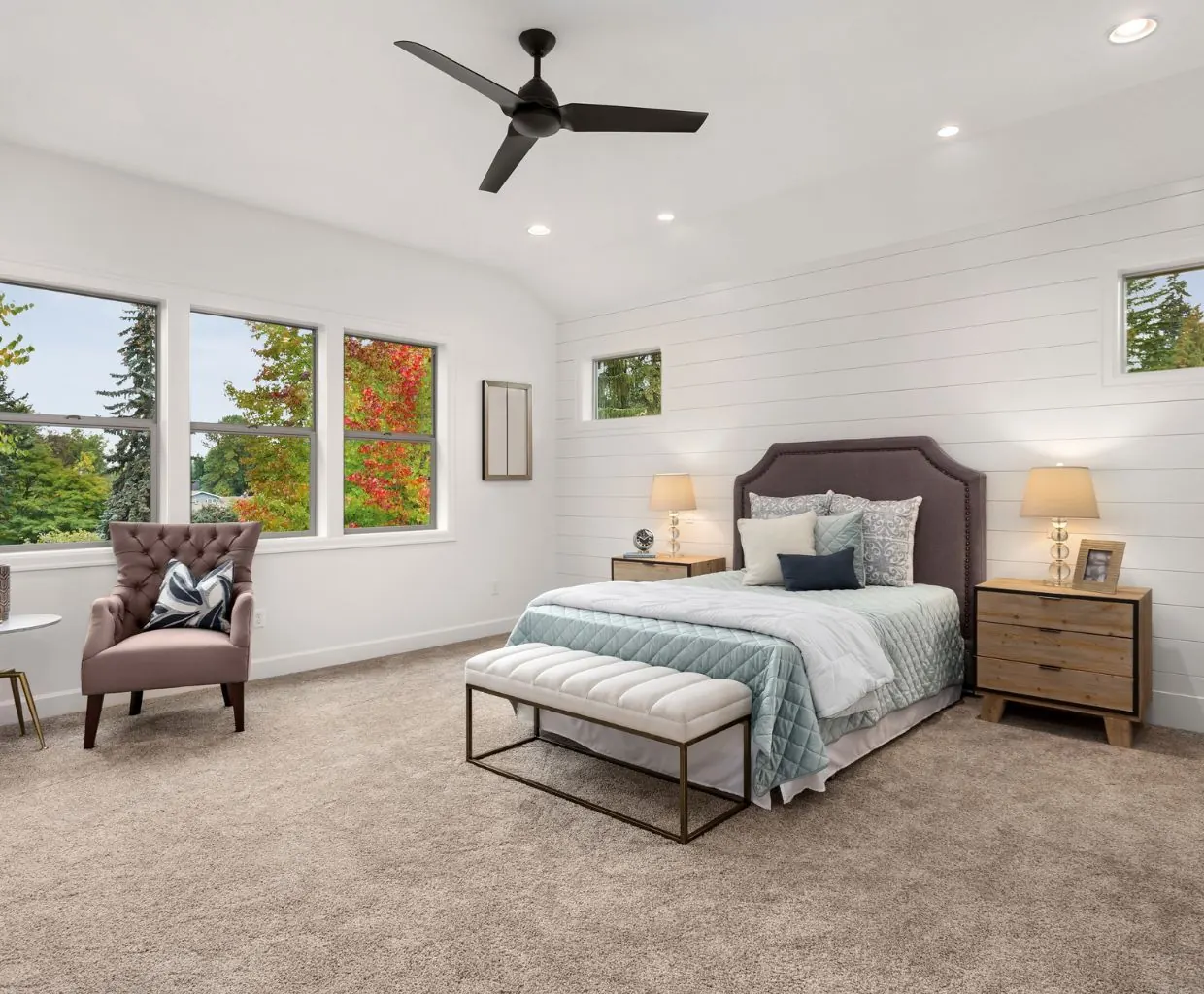 Bright bedroom with a white ceiling fan above a bed with a tufted headboard and a bench at its foot