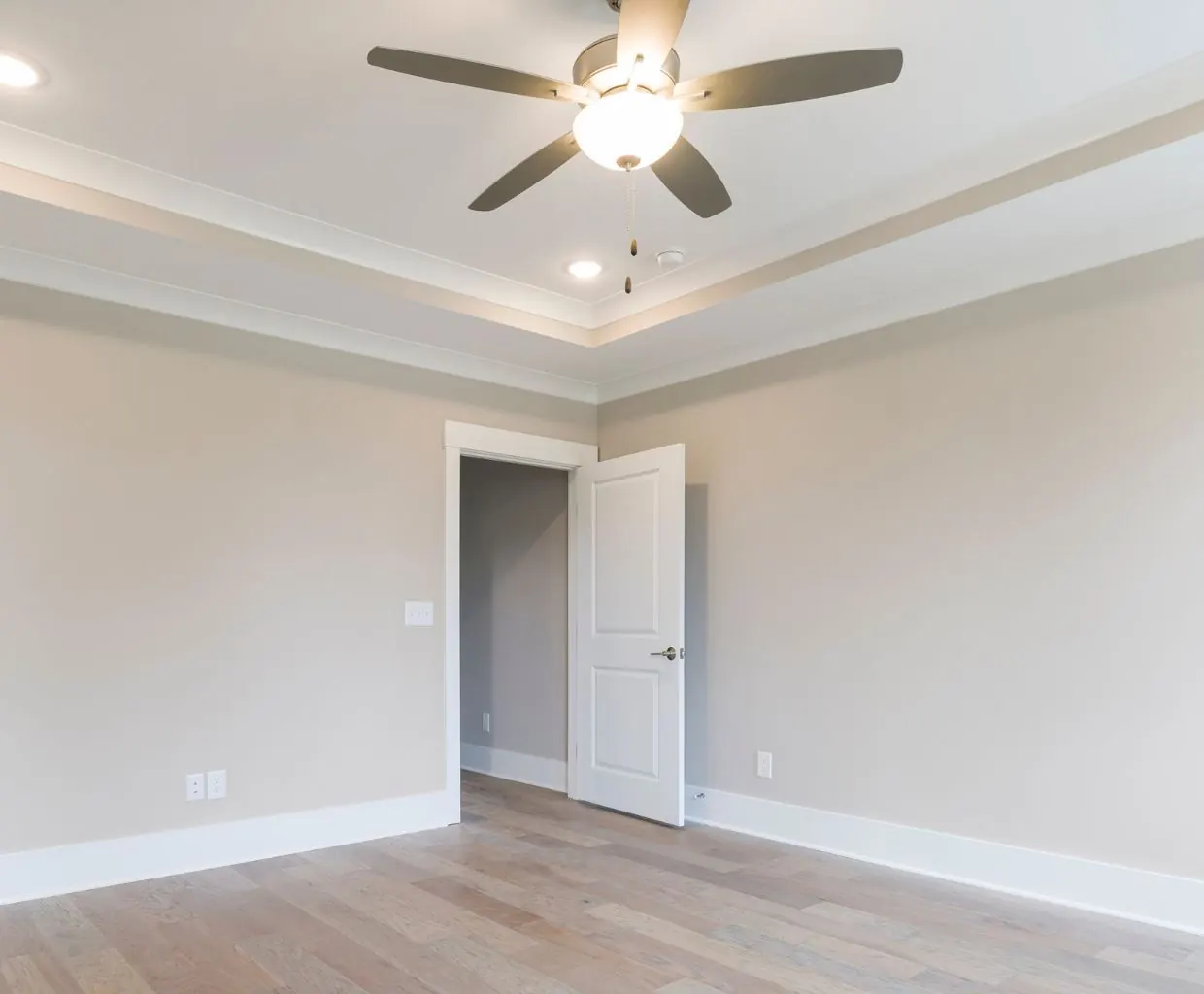 Empty bright room with a white ceiling fan and light kit above a wood floor