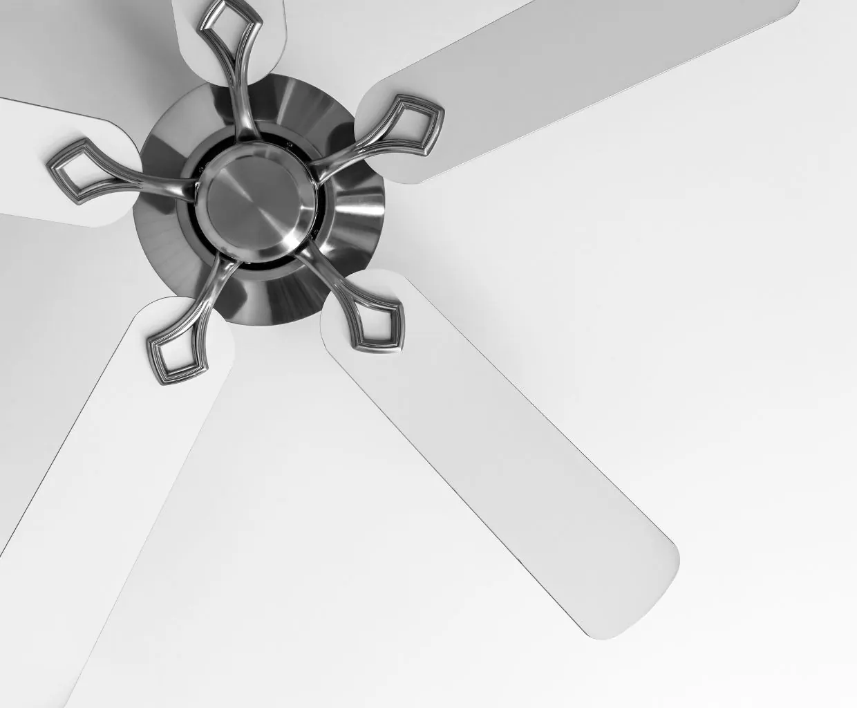 Looking up at a five-blade ceiling fan with white blades and polished nickel blade arms against a white ceiling